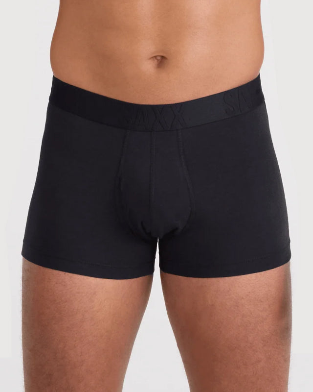 Model wearing black SAXX trunks on a plain background