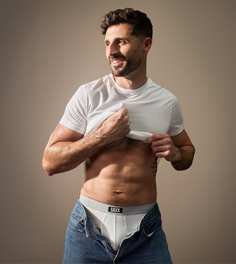 Model wearing white underwear with unbuttoned jeans and white t-shirt